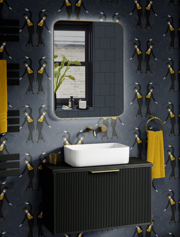 Black and mustard cabaret wallpaper in a dramatic bathroom with black vanity and yellow towels