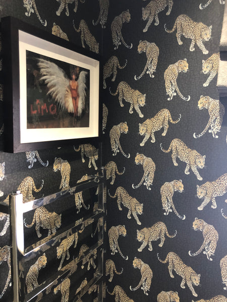 Charcoal leopard wallpaper used in a bathroom with black vanity, mirror, window and bold animal print wall